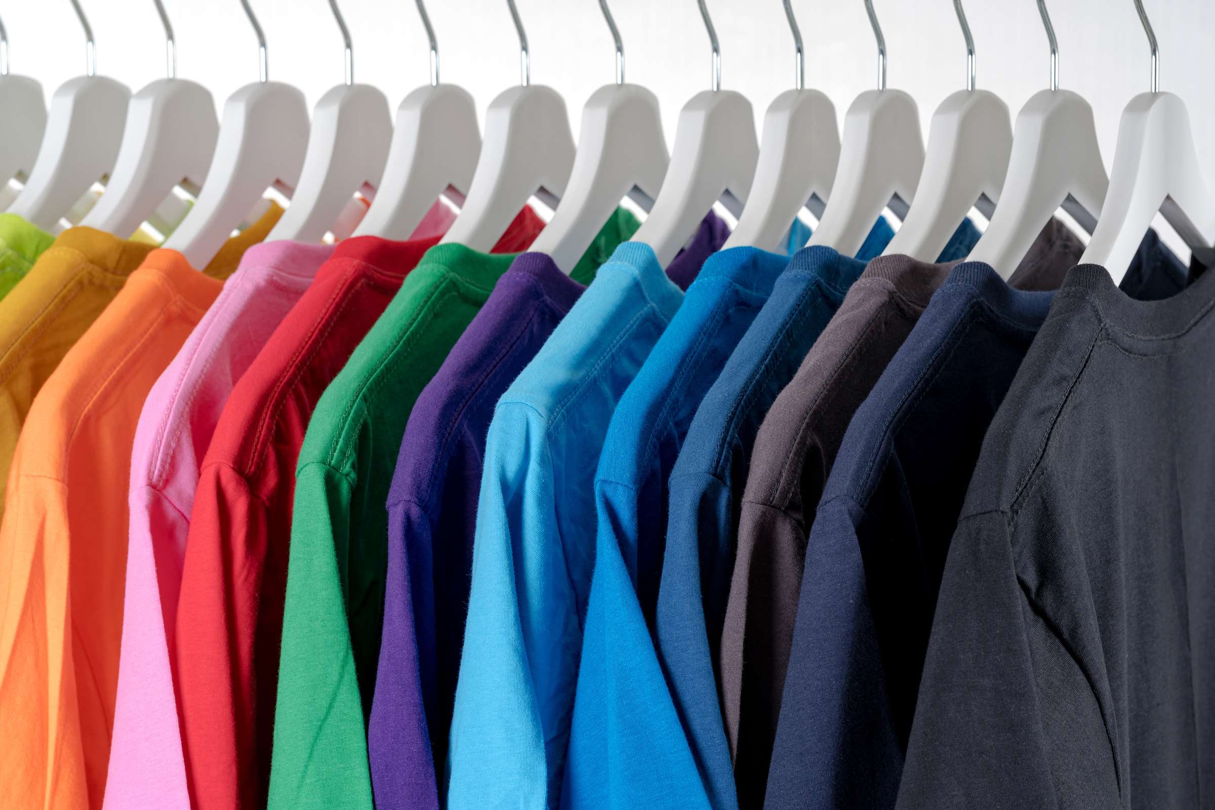 Row of multicolored similar clothes on hangers